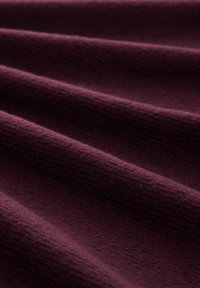 Textielstof in diep paars, met een zachte, geribbelde textuur en een licht glanzende glans, die zachte plooien en golven laat zien.