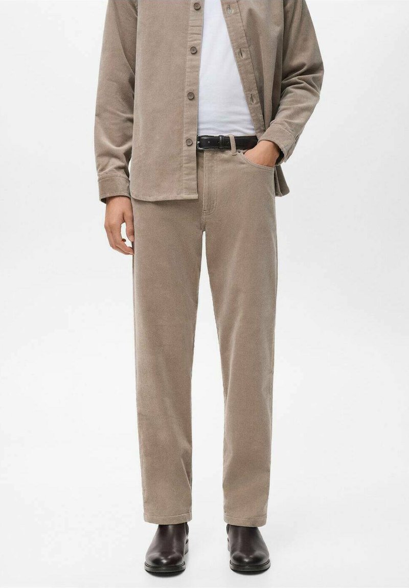 Pantalones de pana beige con un corte relajado, que cuentan con bolsillos laterales y un cinturón. Llevados con una camisa de botones beige a juego.