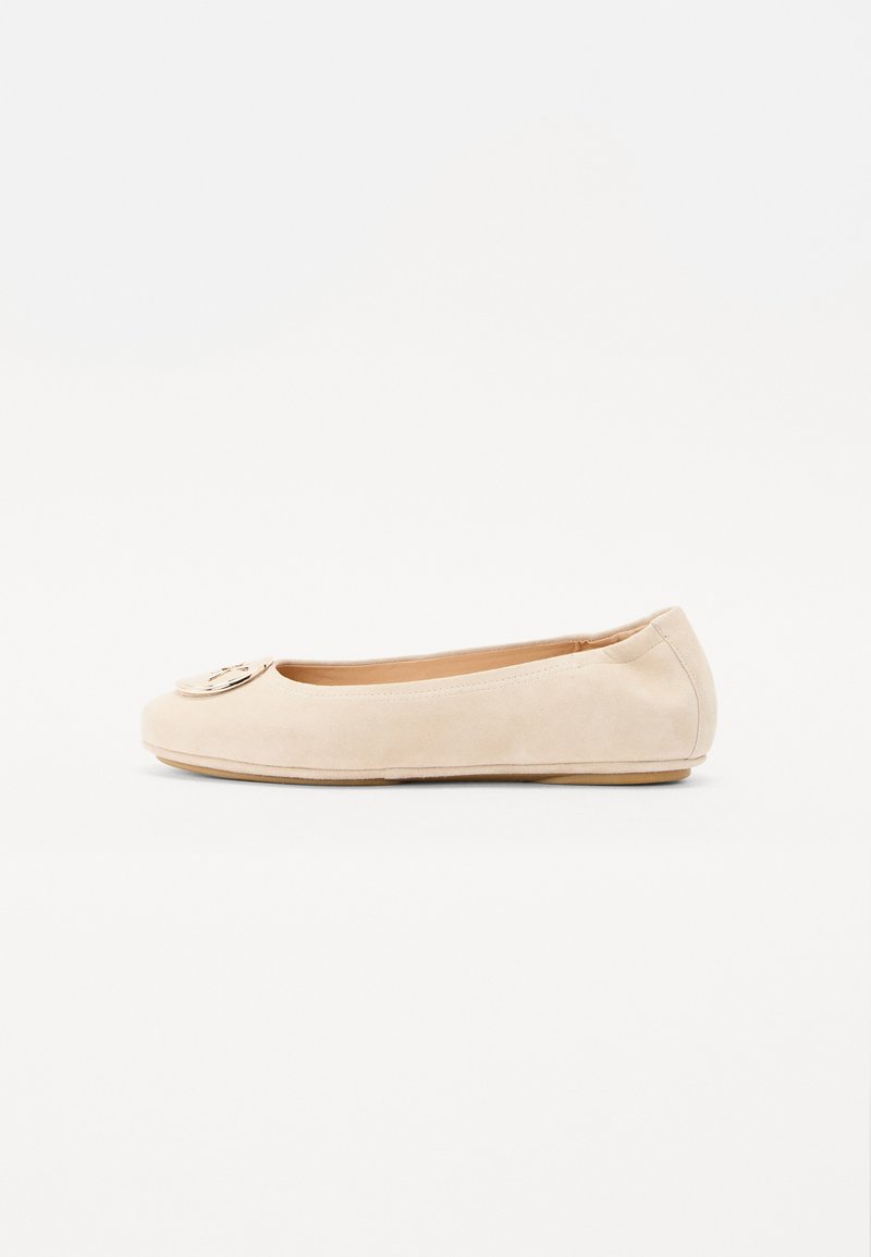 Ballerines en suède beige avec un bout rond et un emblème doré décoratif à l'avant. Texture lisse avec une semelle fine et flexible.