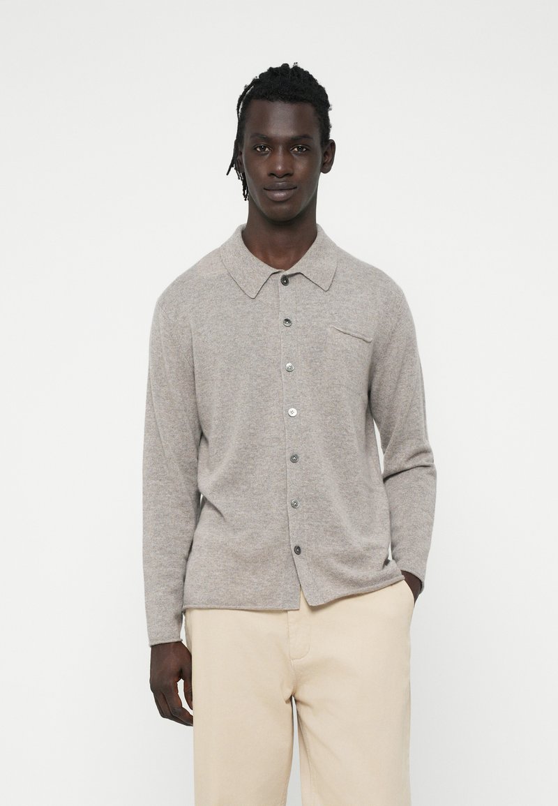 Cardigan in lana grigia chiara con collo a camicia, bottoni frontali e una piccola tasca sul petto. Tessuto liscio e maniche a tutta lunghezza.