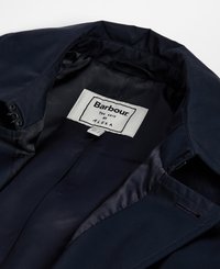 Wnętrze granatowej kurtki z gładką fakturą, metka z napisem "Barbour The Edit by Alexa" oraz zapięcie na guzik na kołnierzu.