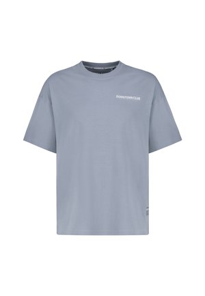 Helles blaues Oversized-T-Shirt mit dem Text "DOWNTOWN CLUB" auf der linken oberen Brust und einem kleinen Etikett nahe dem unteren Saum.