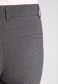 Pantaloni grigi strutturati con un tessuto liscio e testurizzato. Presentano una tasca posteriore piatta e una vita dritta. Design professionale.
