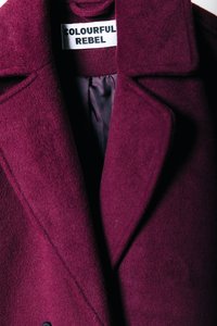 Casaco de lã burgundy com gola com picos, lapelas e um forro interior suave. Etiqueta com a inscrição "COLOURFUL REBEL." Tecido texturizado.