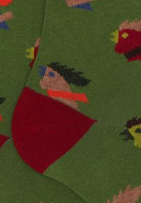 Calze di cotone con uno sfondo verde che presenta motivi di personaggi dei cartoni animati colorati. Accenti rossi nella zona delle dita, texture a coste.