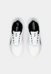 Baskets blanches avec un dessus en mesh texturé, intérieur noir et un design minimaliste. Dotées de lacets et d'un branding subtil sur la languette.