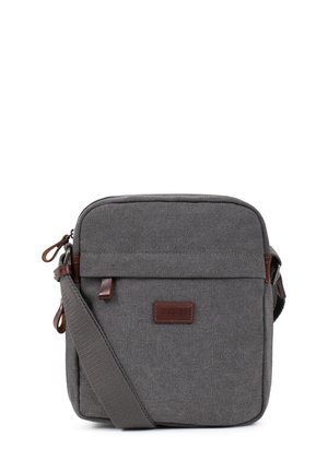 Sac bandoulière compact en toile grise avec sangle réglable, tirettes de fermeture éclair en cuir marron et écusson logo sur la poche avant.