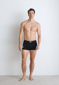 Zwarte bokser shorts gemaakt van elastisch materiaal met een strak figuur. Voorzien van een wit logo op de tailleband en een gladde stofstructuur.