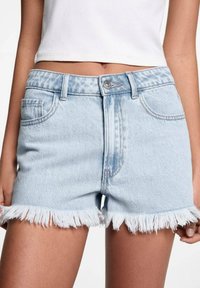 Svijetloplavi traper šorts s izrezanim rubom, pet džepova i metalnim kopčanjem. Ima srednji pojas i ravni kroj.