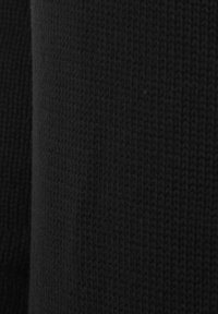 Schwarzer Strickstoff mit einer strukturierten Oberfläche, die komplizierte Stiche und ein weiches Erscheinungsbild zeigt. Die Kanten sind leicht gerollt.