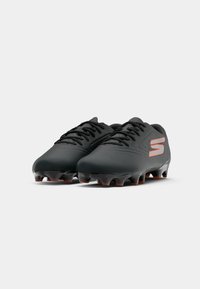 Black football cleats with a smooth material, featuring a textured toe box and a prominent orange "S" logo on the side.