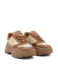 Chunky Sneakers mit einem beigefarbenen gemusterten Stoff, der Reisestempel zeigt, und braunen Lederelementen. Dicke Gummisohle, runde Zehenpartie und Schnürdesign.