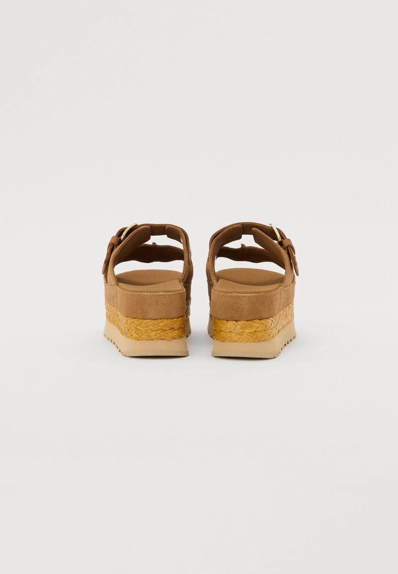 Bruine suède wedge sandalen met een textuur jute tussenzool en een beige rubberen buitenzool. Voorzien van een verstelbare gespriem aan de achterkant.