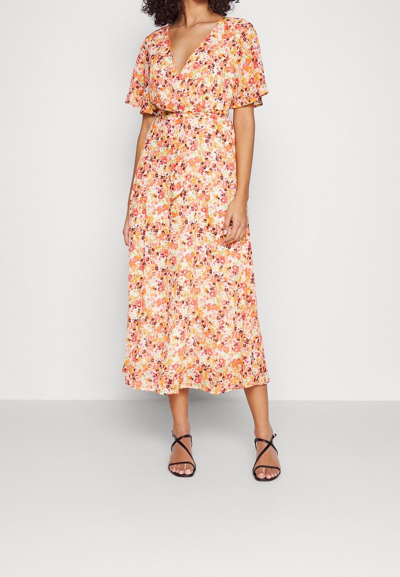 Robe longue fleurie aux tons orange et rose, avec des manches courtes volantées, un décolleté en V croisé et une taille cintrée pour une silhouette définie.