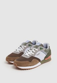 Sneaker marroni e verdi con tomaia in rete e camoscio, lacci bianchi e suola in gomma testurizzata con un accento arancione sul tallone.