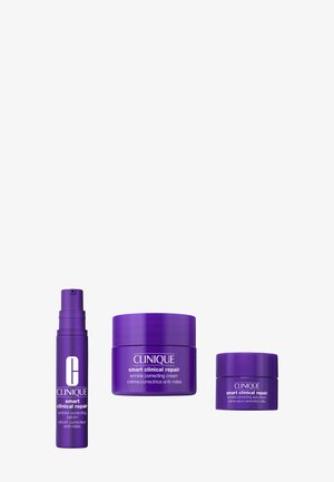 Drei violette Clinique-Produkte: Falten korrigierendes Serum in einer Pumpflasche, Falten korrigierende Creme in einem Tiegel und Augencreme in einem kleinen Tiegel.