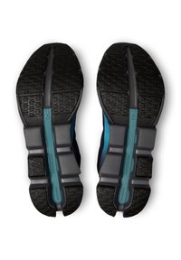 Semelles de chaussures en caoutchouc noir avec un motif de grip texturé. Comprend une section grise au milieu et un accent turquoise le long du centre.