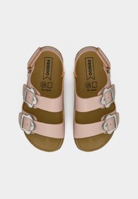 Παιδικά ροζ δερμάτινα σανδάλια με διπλές ασημένιες αγκράφες και ρυθμιζόμενα λουράκια στο πίσω μέρος, τοποθετημένα επίπεδα σε λευκό φόντο.