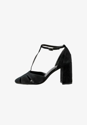 Schwarze Wildleder-T-Strap-Schuhe mit Blockabsatz und spitzem Zehenbereich, Ausschnitt-Design und verstellbarem Knöchelriemen. Glatte Innenauskleidung.