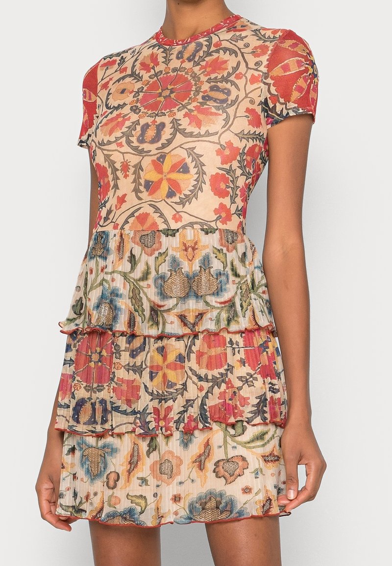 Robe à volants avec un motif floral multicolore, un corsage cintré, des manches courtes et des détails de bord à volants. Fabriquée en tissu léger.