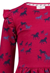 Rotes langärmeliges Kleid mit einem Muster aus marineblauen Pferden und glitzernden Akzenten. Rüschen-Details an den Schultern; ein geraffter Saum des Rocks.