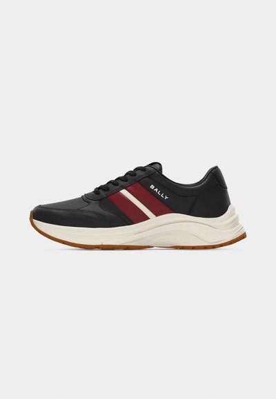 Baskets en cuir noir avec des bandes bordeaux et blanches, semelle épaisse beige clair, semelle extérieure marron, et marquage "BALLY" sur le côté.