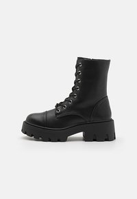 Black leather ankle boots with a chunky sole, lace-up front, reinforced toe, and smooth texture. Features metal eyelets for laces.