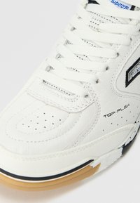 Scarpa sportiva bianca con tomaia in morbida pelle, punta perforata, design con lacci e suola in gomma nera e color gomma a contrasto.