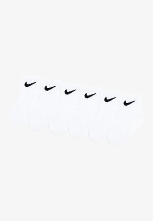Six paires de chaussettes blanches pour chevilles disposées côte à côte, chacune avec un petit logo Nike swoosh noir près du bord supérieur.