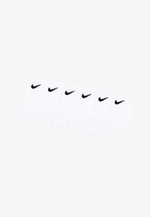 Zes paar witte enkelsokken naast elkaar gelegd, elk met een klein zwart Nike-swoosh logo bij de bovenste boord.