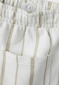 Hvid tekstureret stof med beige striber; har et elastisk taljebånd med en knap og en lomme på siden.