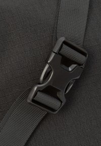 Nahaufnahme eines schwarzen Nylonriemens und einer Kunststoffschnalle auf einem dunklen strukturierten Hintergrund, entworfen zum Sichern von Gegenständen oder Taschen.