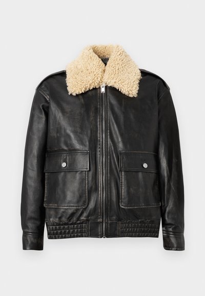 Veste en cuir noir avec un col en shearling beige, fermeture éclair et deux poches avant avec boutons pression. Présente une taille et des poignets côtelés.