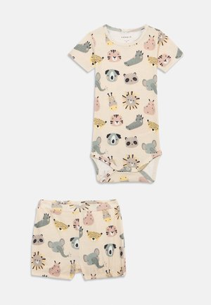 Conjunto de algodão para bebé composto por um bodies de manga curta e calções, ilustrado com caras de animais coloridas sobre um fundo bege claro.