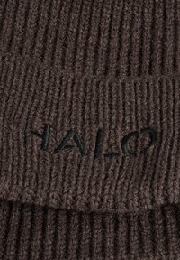 Dunkelbrauner, gerippter Strickstoff mit teilweise sichtbarem schwarzen Sticktext, der "HALO" lautet.