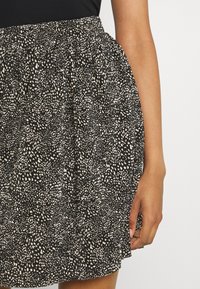 Jupe noire et crème à motifs avec une taille élastique, dotée d'un design plein et froncé, et de légers volants à l'ourlet.