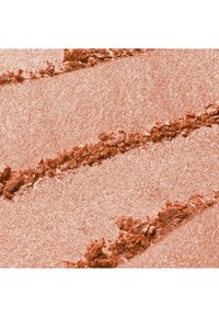 Poudre dorée rose scintillante avec des lignes texturées et des zones écrasées sur une surface plate, ressemblant à du maquillage ou du pigment écrasé.