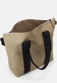 Beige színű vászontáska, tartós anyagból, fekete nylon fogantyúkkal, tágas nyitott tetejével és minimalista dizájnnal.