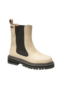 Bottines en cuir beige avec des panneaux élastiques noirs sur les côtés, bout arrondi, semelle épaisse en caoutchouc noir et détails de surpiqûres blanches contrastantes.