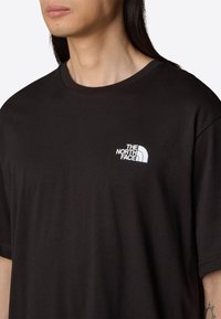 Sort bomulds T-shirt med rund halsudskæring og korte ærmer. Har et hvidt logo af "The North Face" på venstre bryst. Simpel design.