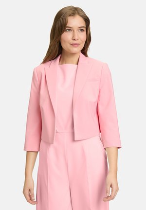 Blazer rose taillé avec des manches trois-quarts, en tissu lisse, col à revers et une poche poitrine, porté sur un haut assorti.
