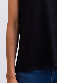 Sort ærmeløs top med en blød tekstur og lige kant. Kombinationen med blå denim jeans fremhæver en tætsiddende silhuet på kroppen.
