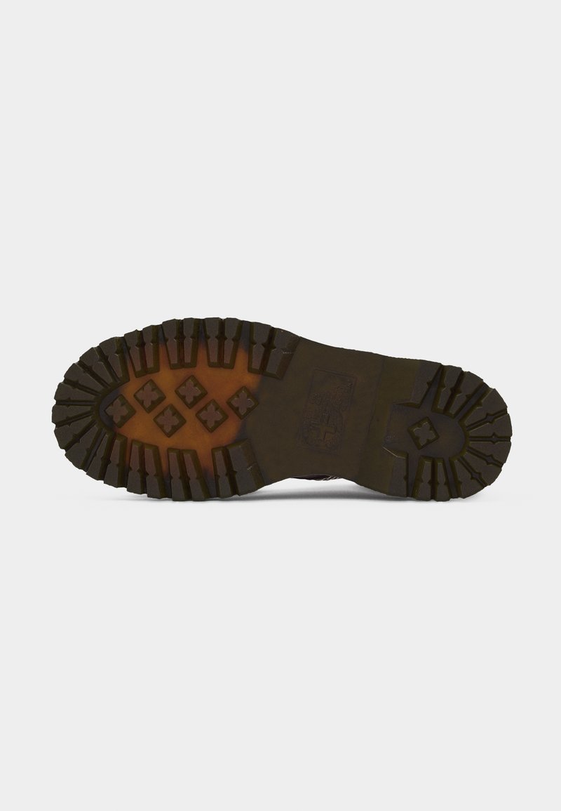 Sole of a dark brown boot with deep treads featuring cross-shaped and rectangular patterns on a light grey background.