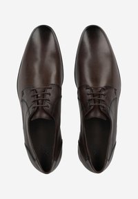 Bruine leren schoenen met een gladde afwerking, ronde neus en subtiele stiksels. Voorzien van een vetersluiting en een lichte hak.