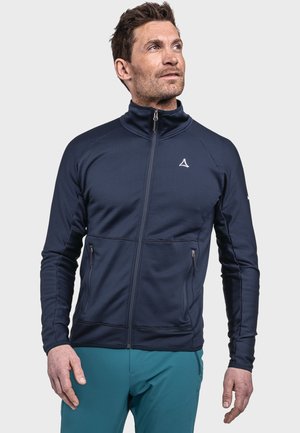 Navy zip-up jacket with a textured fabric, two side pockets, and a white logo on the chest. Features a high collar and fitted design.