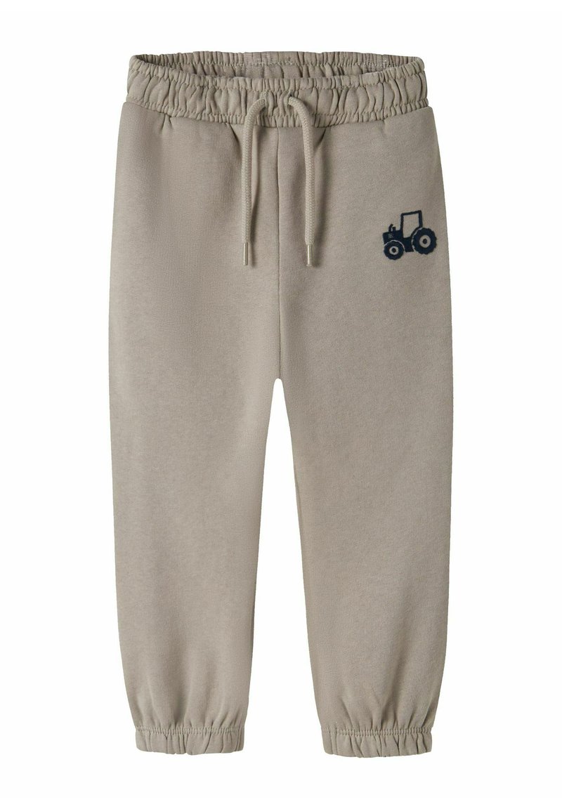 Beżowe spodnie dresowe z sznurkiem w pasie i elastycznymi mankietami, z granatową grafiką traktora na lewej uda.