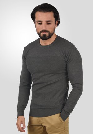 Suéter gris de punto con cuello redondo, mangas largas y costuras texturizadas en el pecho. Cintura ajustada y puños acanalados.