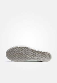 Sole di scarpa in gomma bianca con una piccola texture circolare, "Paul Green" impresso sulla superficie e un design di bordo liscio e curvo.