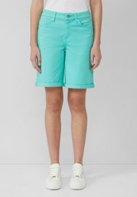 Shorts en denim turquoise avec ourlets retroussés, dotés de cinq poches et d'une fermeture à bouton. Associés à des baskets blanches sur un fond neutre.