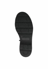 Semelle de chaussure en caoutchouc noir avec une surface texturée, présentant des rainures horizontales et un logo estampé indiquant "CAPRICE" et la taille "37."
